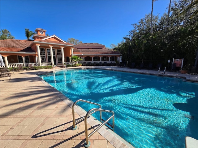 community pool with a patio area and fence