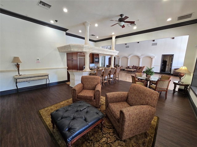 living room featuring decorative columns, visible vents, and dark wood finished floors