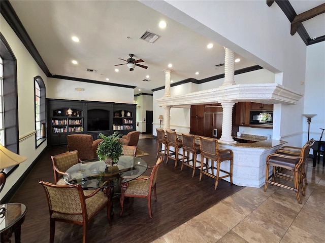 dining space with a towering ceiling, ornate columns, visible vents, and crown molding