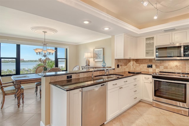 8779 Midnight Pass Rd Unit 406H, Sarasota, FL 34242 - kitchen with stainless steel appliances, crown molding, a peninsula, light tile patterned flooring, and backsplash