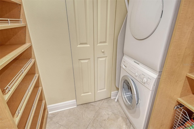 8779 Midnight Pass Rd Unit 406H, Sarasota, FL 34242 - laundry room with stacked washing machine and dryer, light tile patterned floors, and baseboards