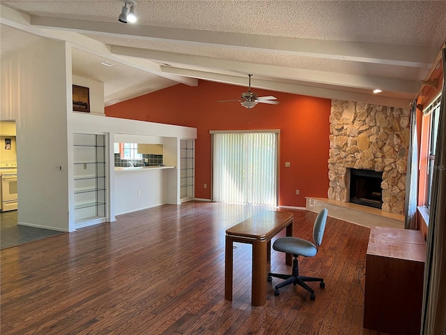 office featuring lofted ceiling with beams, a healthy amount of sunlight, wood finished floors, and a stone fireplace