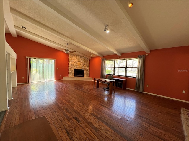 unfurnished living room featuring vaulted ceiling with beams, a textured ceiling, a stone fireplace, visible vents, and wood-type flooring