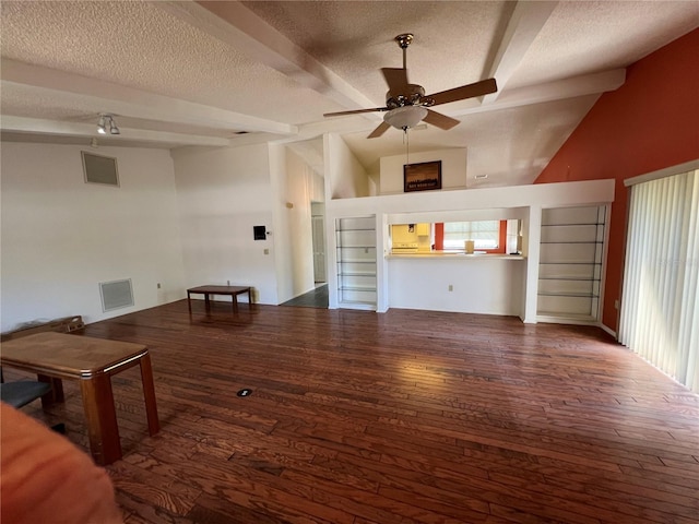 unfurnished living room with visible vents, vaulted ceiling with beams, a textured ceiling, and wood finished floors