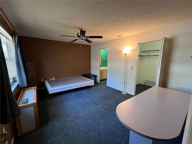 unfurnished bedroom featuring a textured ceiling, dark colored carpet, a baseboard radiator, and visible vents