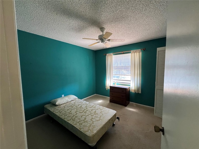 bedroom featuring baseboards, a textured ceiling, a ceiling fan, and carpet flooring