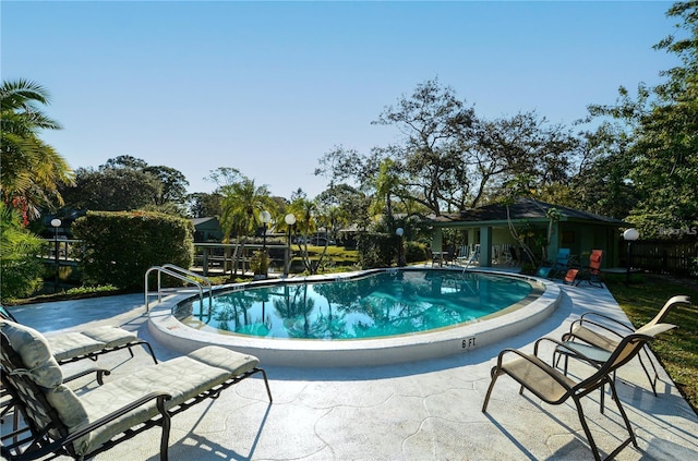 community pool with a patio and fence