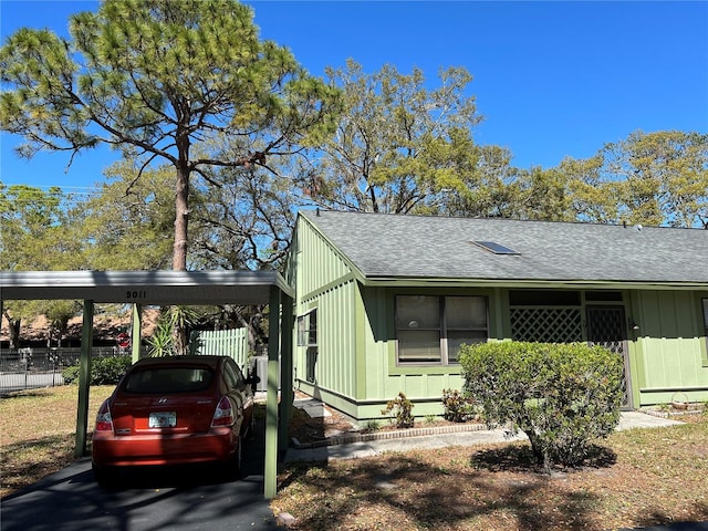 view of side of property featuring a shingled roof and fence