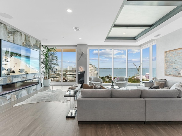 living room with visible vents, a water view, wood finished floors, and floor to ceiling windows