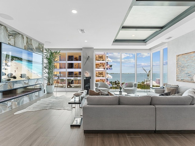 living area featuring visible vents, a water view, expansive windows, wood finished floors, and recessed lighting