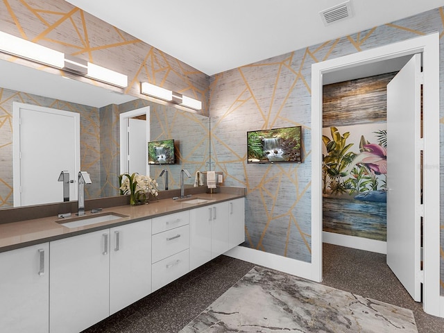 bathroom with double vanity, baseboards, visible vents, and a sink