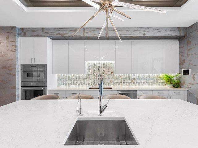 kitchen with a sink, modern cabinets, appliances with stainless steel finishes, and white cabinetry