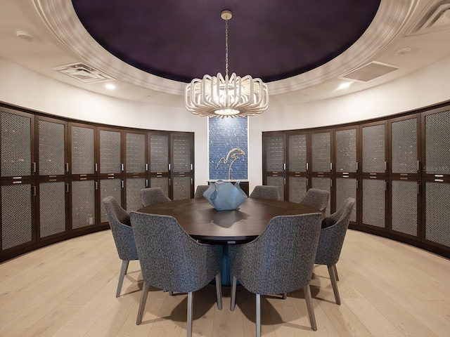 dining area with visible vents, a raised ceiling, wood-type flooring, and ornamental molding