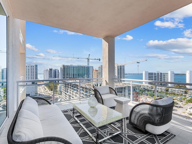 balcony with a city view, outdoor lounge area, and a water view