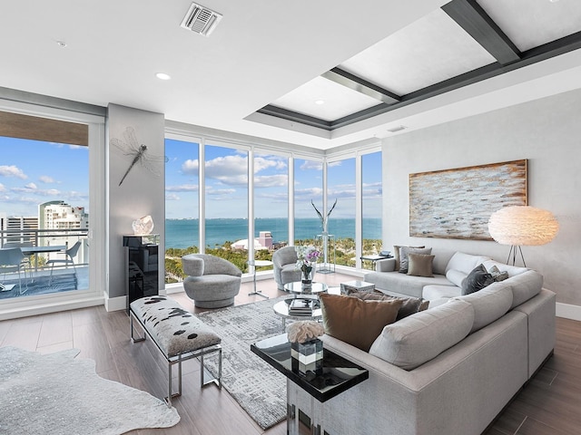 living area with visible vents, baseboards, a water view, floor to ceiling windows, and wood finished floors