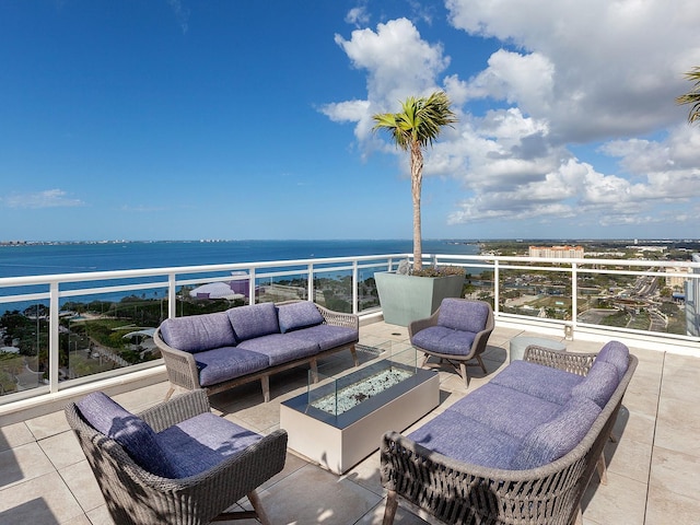 view of patio with a water view, a balcony, and an outdoor living space with a fire pit