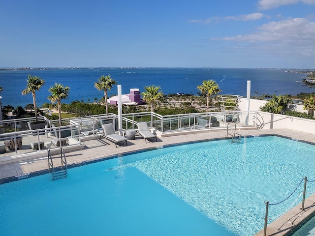 community pool with a water view and a patio area