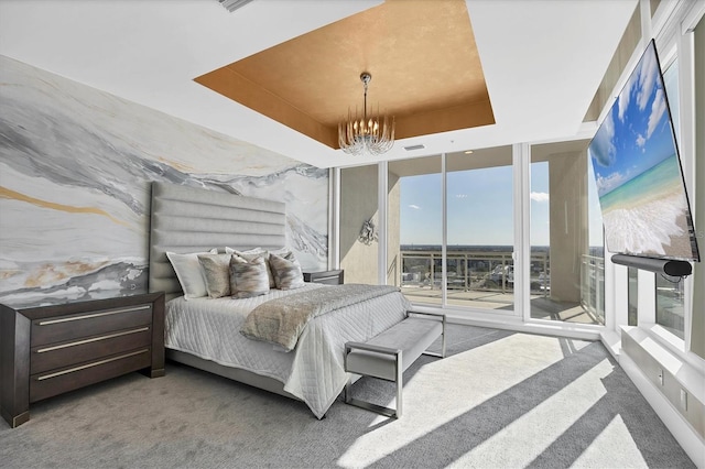 carpeted bedroom with access to exterior, a notable chandelier, a raised ceiling, and expansive windows