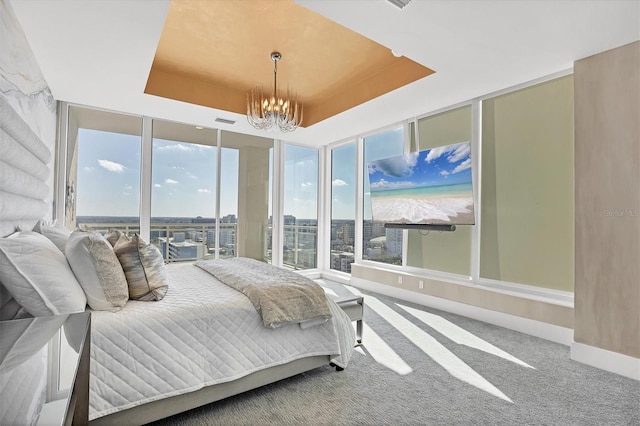 carpeted bedroom featuring visible vents, a raised ceiling, baseboards, and a chandelier