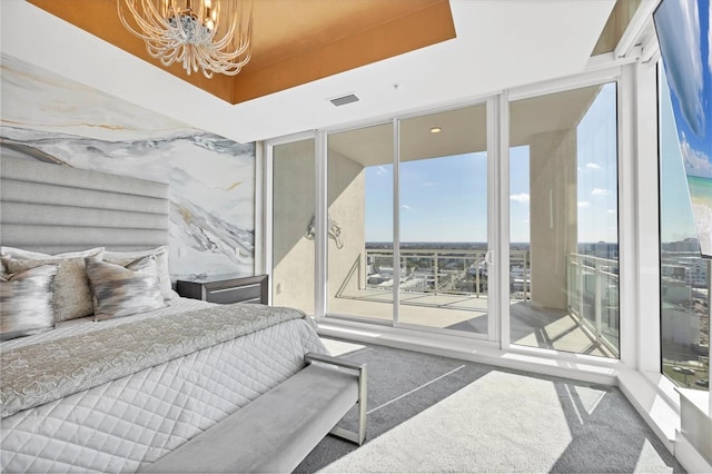 carpeted bedroom featuring a wall of windows, a raised ceiling, access to exterior, and a chandelier