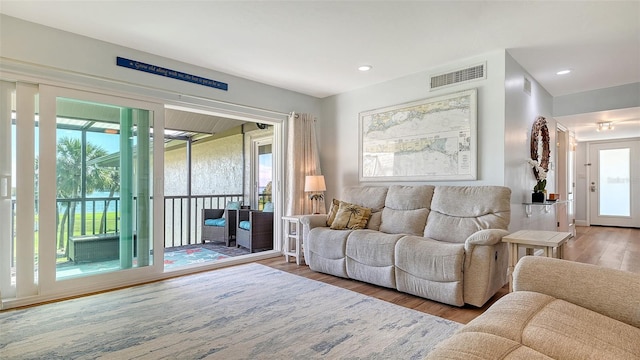 living area with recessed lighting, visible vents, and wood finished floors