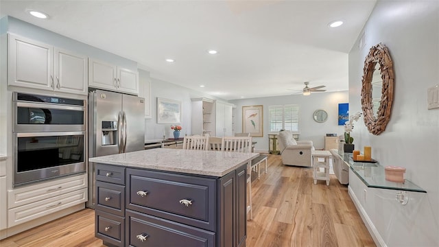 kitchen with light wood-style flooring, recessed lighting, stainless steel appliances, white cabinetry, and a center island