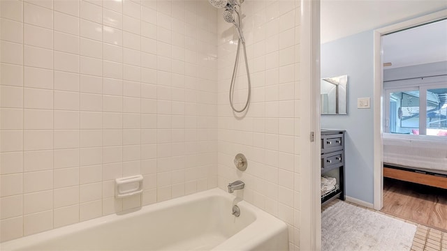 bathroom featuring bathtub / shower combination, ensuite bath, wood finished floors, and baseboards