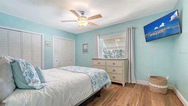 bedroom with ceiling fan, wood finished floors, multiple closets, and baseboards