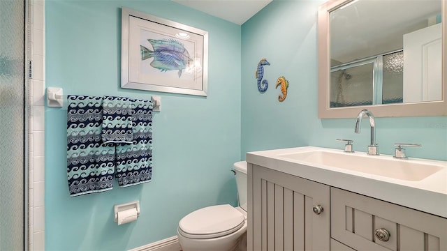 bathroom featuring a shower with shower door, toilet, and vanity