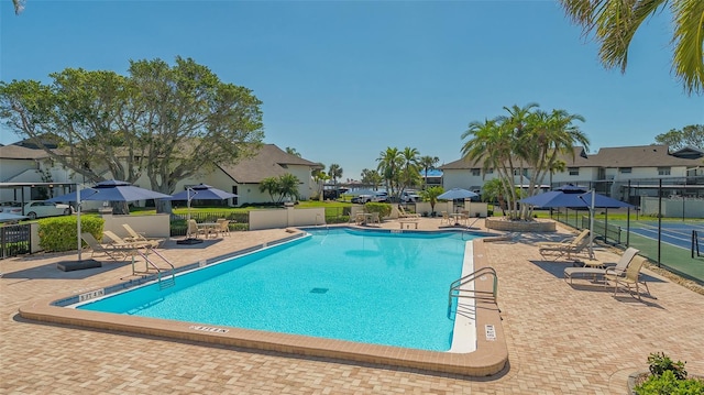 community pool with a residential view, fence, and a patio area