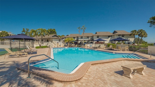 community pool with a residential view, a patio, and fence