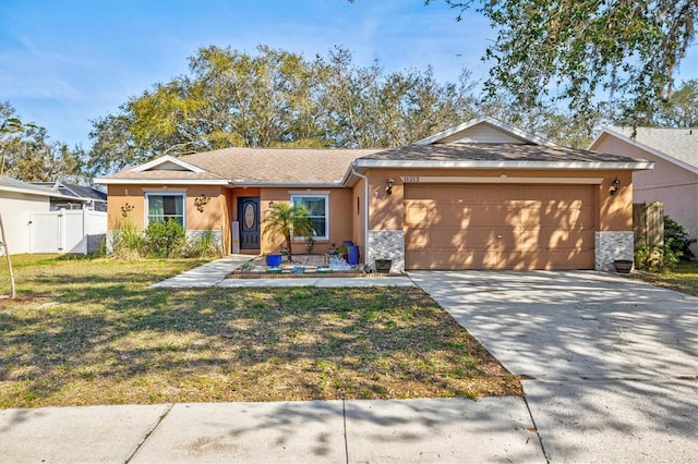 ranch-style house with concrete driveway, an attached garage, fence, a front yard, and stucco siding