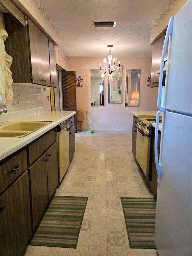 kitchen with range with electric stovetop, visible vents, freestanding refrigerator, a sink, and dishwasher