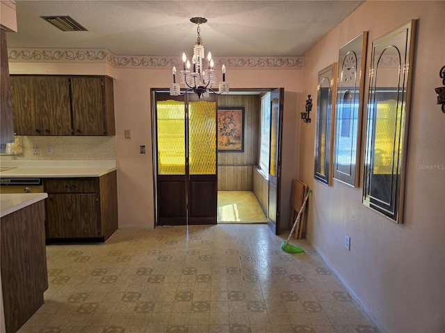 unfurnished dining area with visible vents, baseboards, and an inviting chandelier