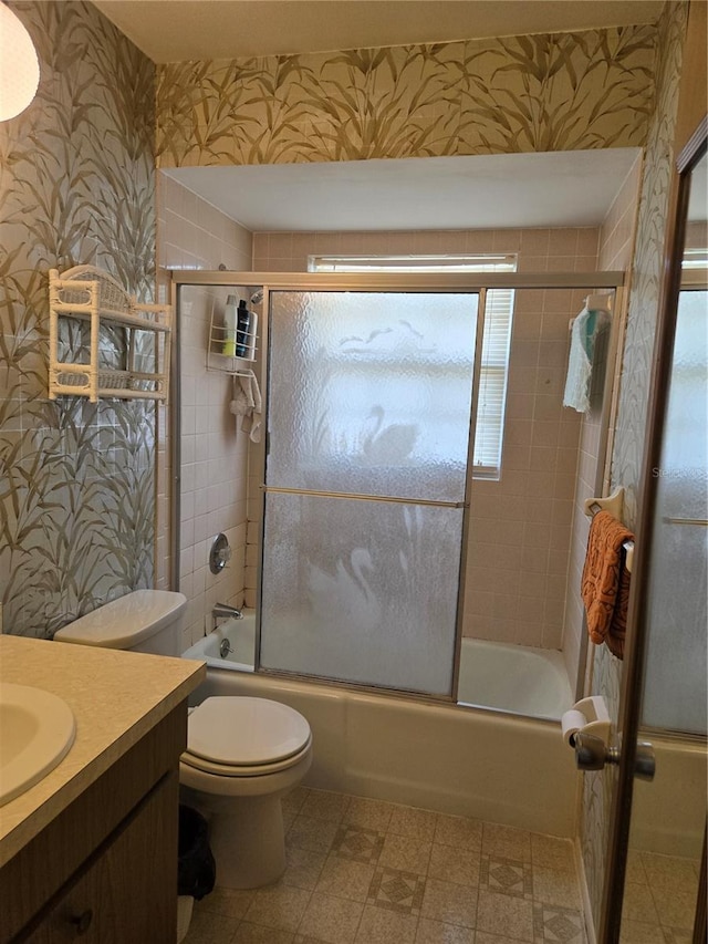 bathroom with wallpapered walls, toilet, combined bath / shower with glass door, vanity, and tile patterned floors