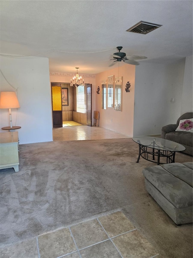 unfurnished living room featuring carpet floors, visible vents, a textured ceiling, and ceiling fan with notable chandelier