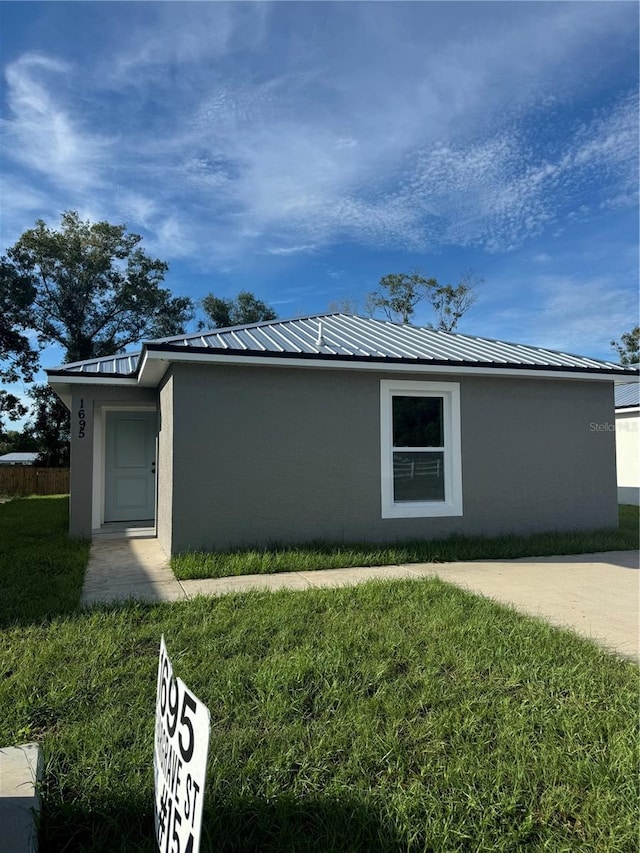 view of home's exterior with metal roof, a lawn, and stucco siding