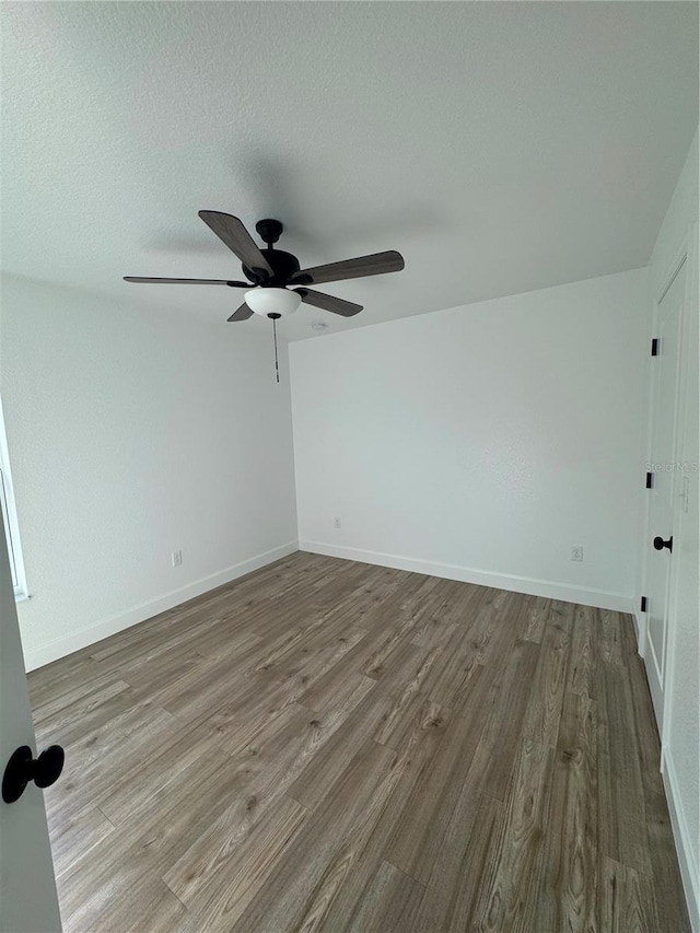 spare room with a textured ceiling, ceiling fan, wood finished floors, and baseboards