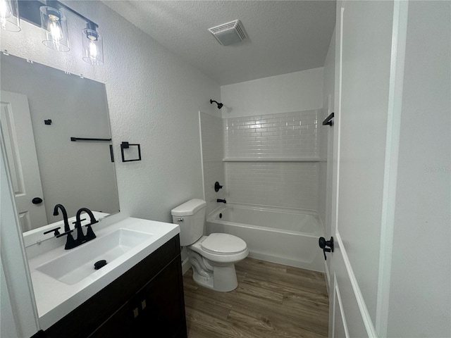 bathroom featuring visible vents, shower / bathing tub combination, toilet, vanity, and wood finished floors