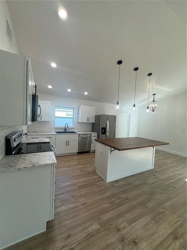 kitchen with visible vents, decorative backsplash, appliances with stainless steel finishes, wood finished floors, and a sink