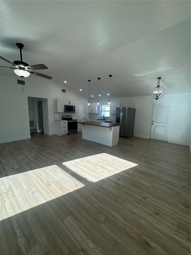 kitchen with lofted ceiling, wood finished floors, white cabinets, open floor plan, and appliances with stainless steel finishes