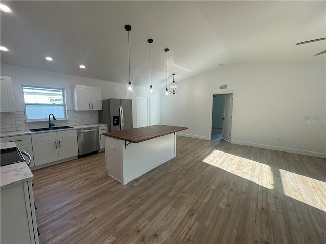 kitchen featuring wood counters, appliances with stainless steel finishes, a sink, and wood finished floors