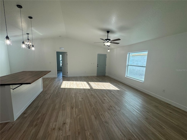 unfurnished living room featuring dark wood-type flooring, vaulted ceiling, baseboards, and a ceiling fan