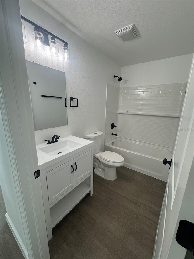 bathroom with shower / bath combination, a textured ceiling, toilet, visible vents, and wood finished floors