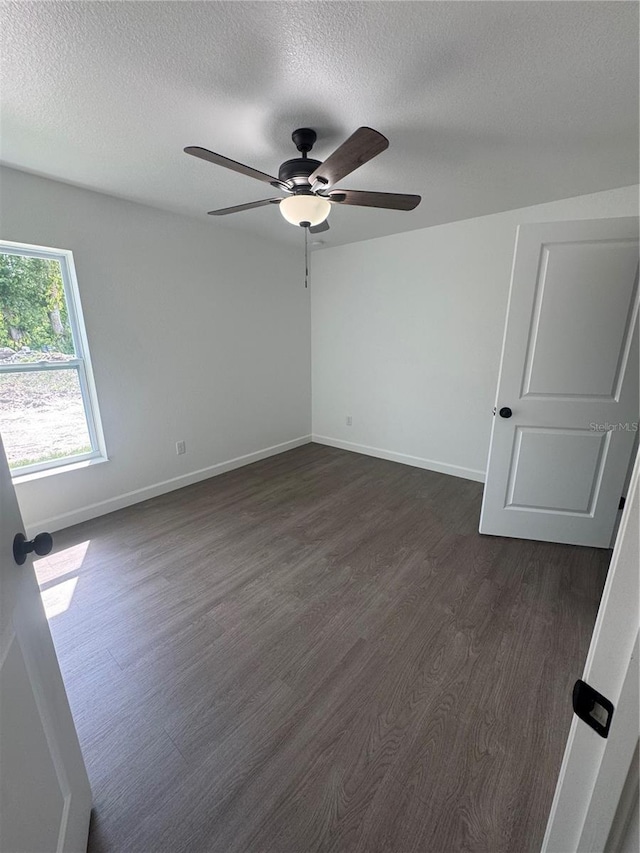 unfurnished room featuring a textured ceiling, dark wood-style flooring, baseboards, and a ceiling fan