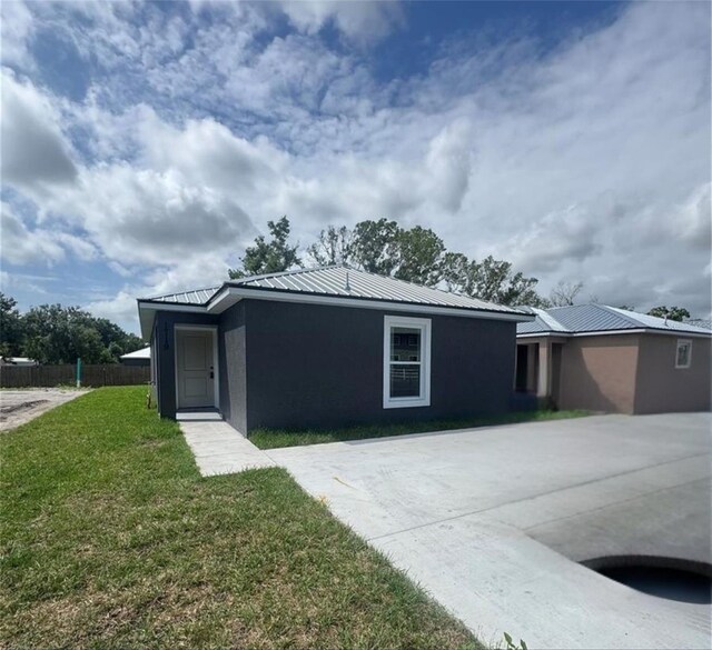 view of front of house featuring metal roof, a front yard, fence, and stucco siding
