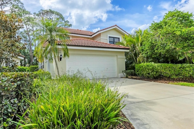 exterior space featuring concrete driveway, a tile roof, an attached garage, and stucco siding