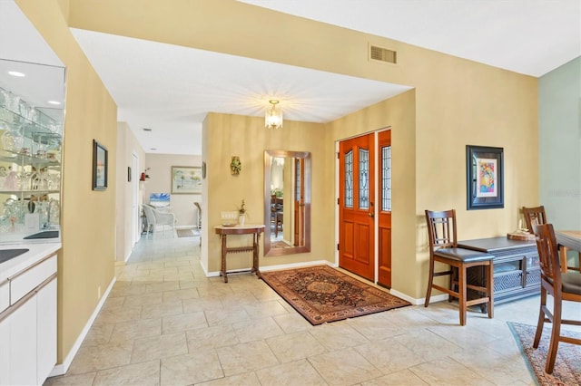 foyer entrance with baseboards and visible vents