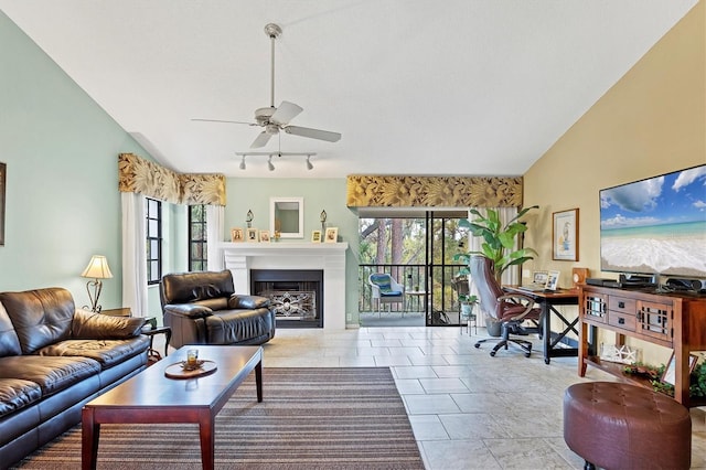 living area with a fireplace, vaulted ceiling, a ceiling fan, and track lighting