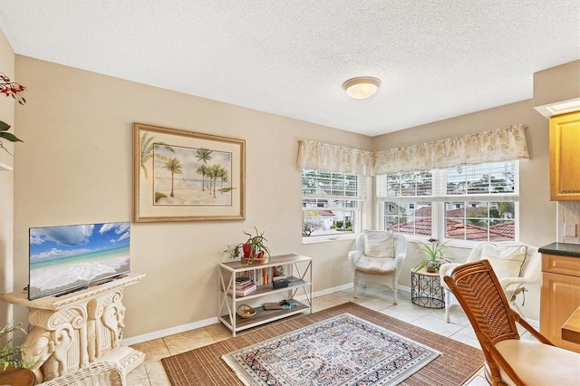 sitting room featuring light tile patterned floors, a textured ceiling, and baseboards